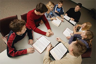 A group of people sitting around a table with some books.