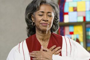 A woman in white and red dress holding her hands to the chest.
