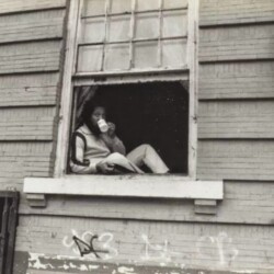 A man sitting in the window of an old building.